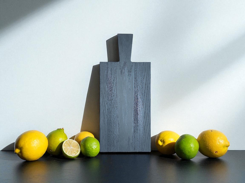 Das Black Snake Board, umgeben von Zitronen und Limetten, zeigt seine Vielseitigkeit als Schneide- und Servierbrett. Ein stilvolles und funktionales Unikat für Ihre Küche.