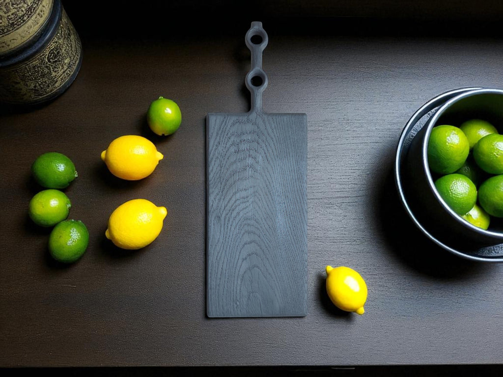 Yakisugi Schneidebrett auf dunkler Arbeitsplatte
Alt-Text (Alt-Attribut): Stilvolles Schneidebrett aus massiver, verkohlter Eiche, mit Yakisugi-Veredelung, das auf einer dunklen Arbeitsplatte lehnt. Im Vordergrund sind Zitronen und Limetten platziert.